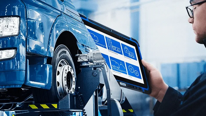 Technik s diagnostickým přístrojem u kola nákladního vozidla